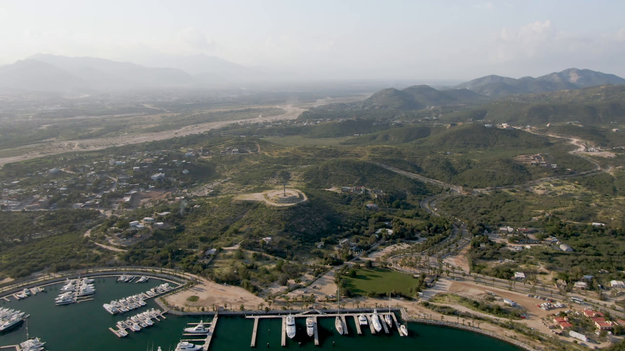 Drone-style view of marina docks below inland hills and a pale riverbed.