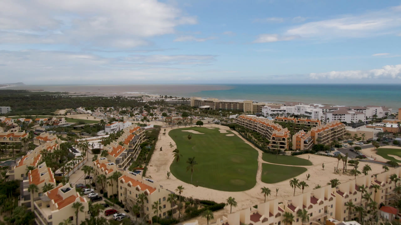 Aerial view of golf course, resort buildings, beach, and ocean