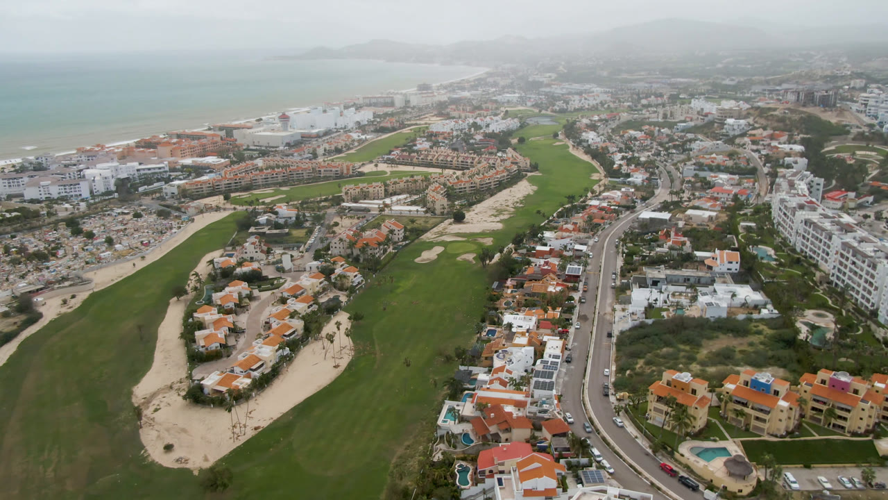 Aerial city and golf course view with beach and ocean beyond.