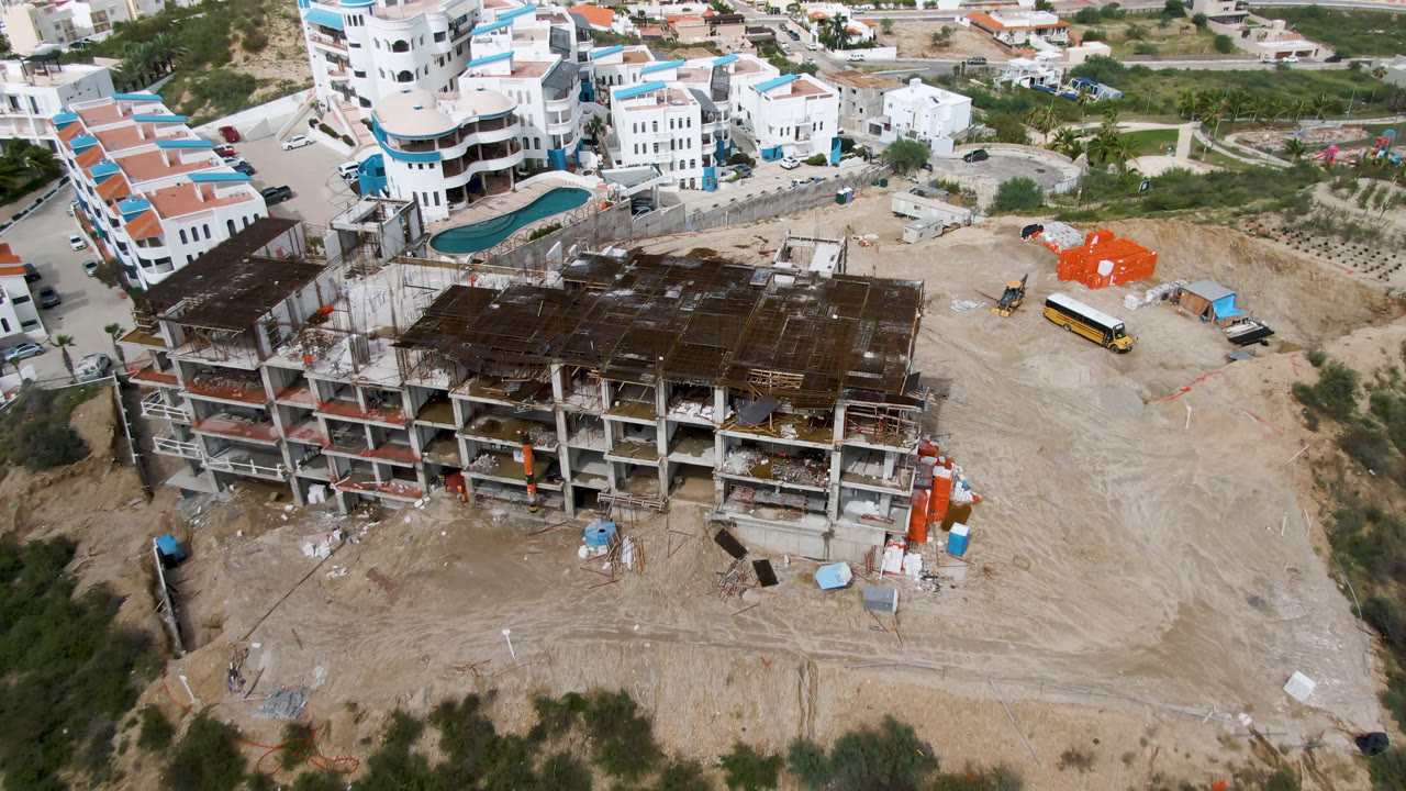 Aerial view of an unfinished concrete building beside roads and white buildings.