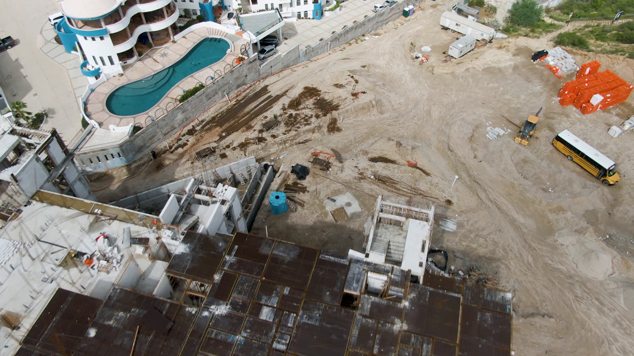 Overhead construction site beside a curved pool and building.