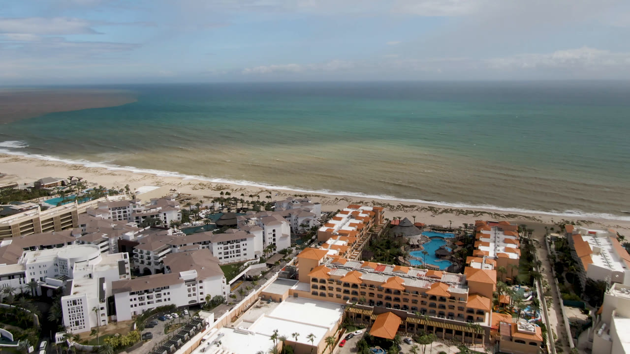 Aerial view of resort buildings beside a sandy shoreline