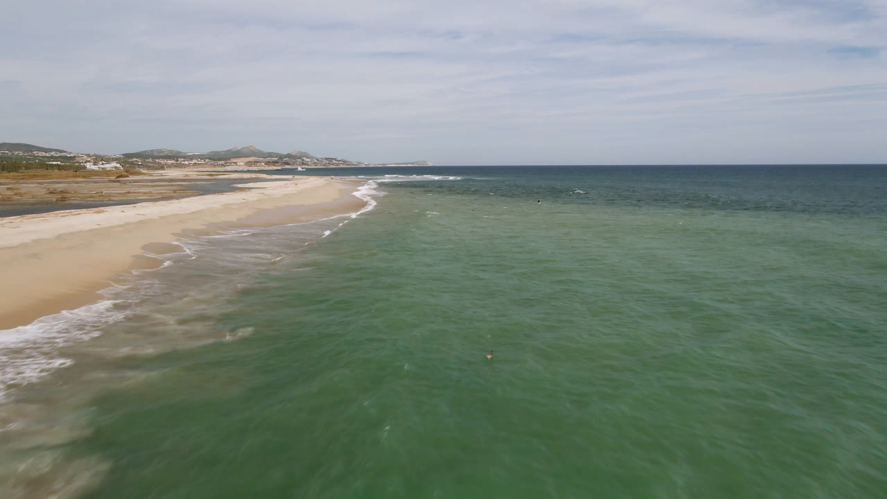 Wide drone view of beach and green ocean water