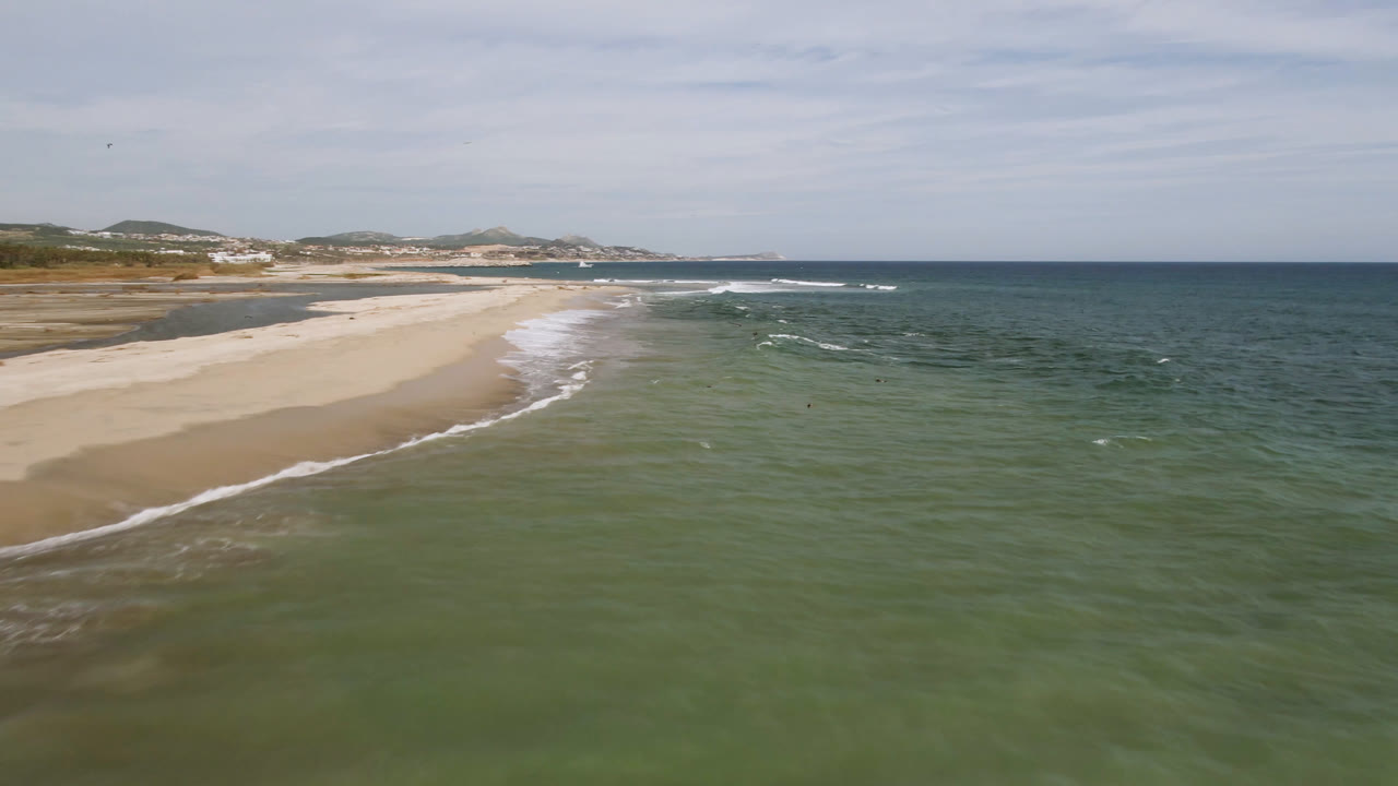 Aerial view of a sandy beach and green-blue ocean waves.