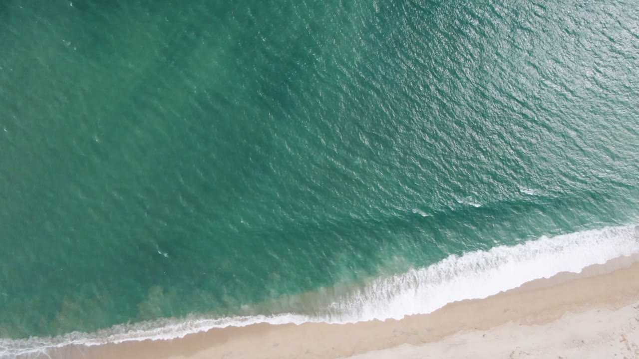 Top-down ocean surface and breaking surf on beach