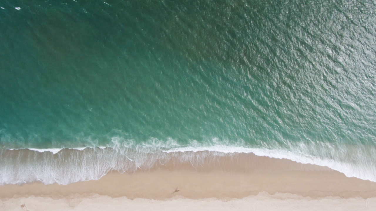 Foamy surf line curving along an empty beach