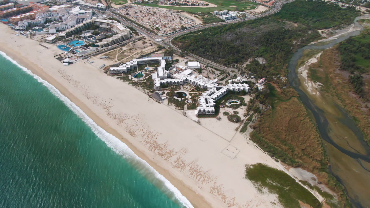 Aerial view of beach, resort buildings, lagoon, roads, and city blocks.