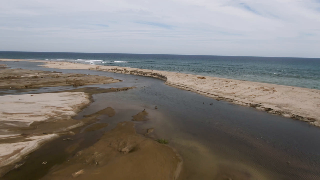 Coastal sand banks and shallow water under a cloudy sky.