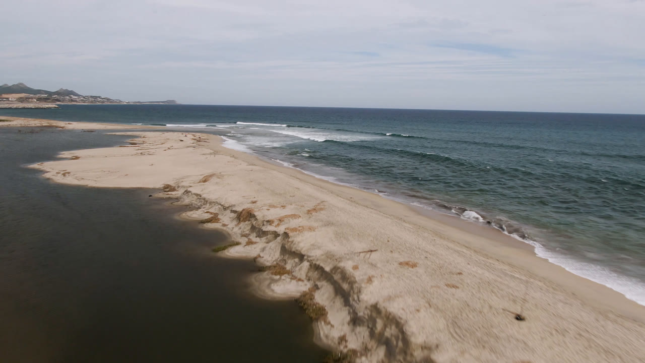 Aerial coastline with dunes, lagoon edge, and breaking waves