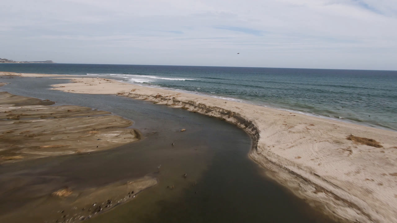 Coastal sand banks with a winding stream and ocean beyond.