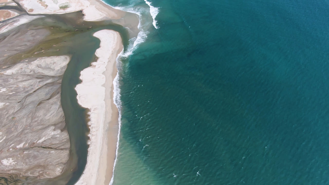 At 0:01, the San Jose del Cabo shoreline remains centered on a narrow bright sand bank, with small white wave breaks on the ocean side and no visible people.
