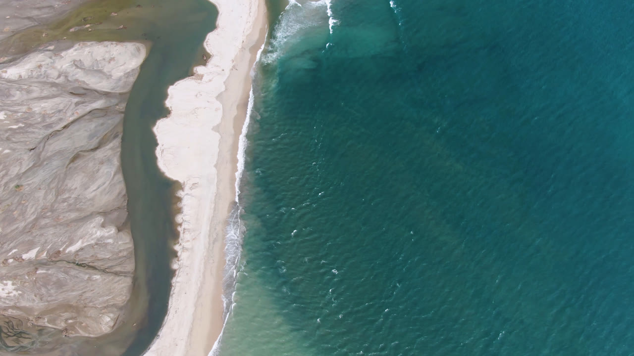 Top-down coastal view with open teal water filling the right side of frame.