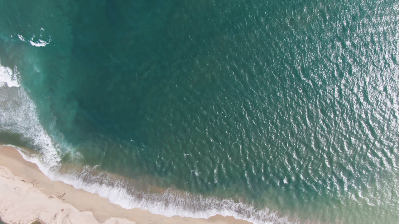Breaking wave and turquoise shallows beside sand