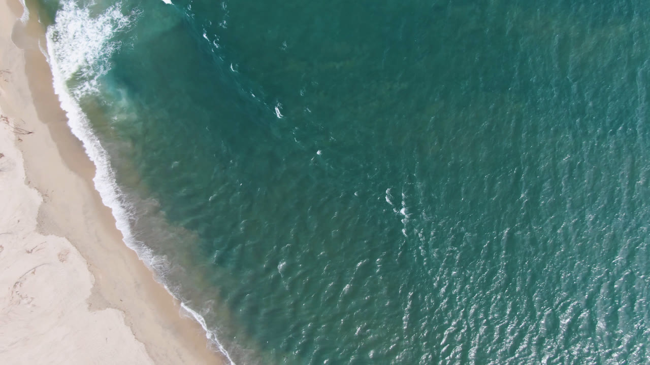 Teal ocean and narrow beach edge seen from above