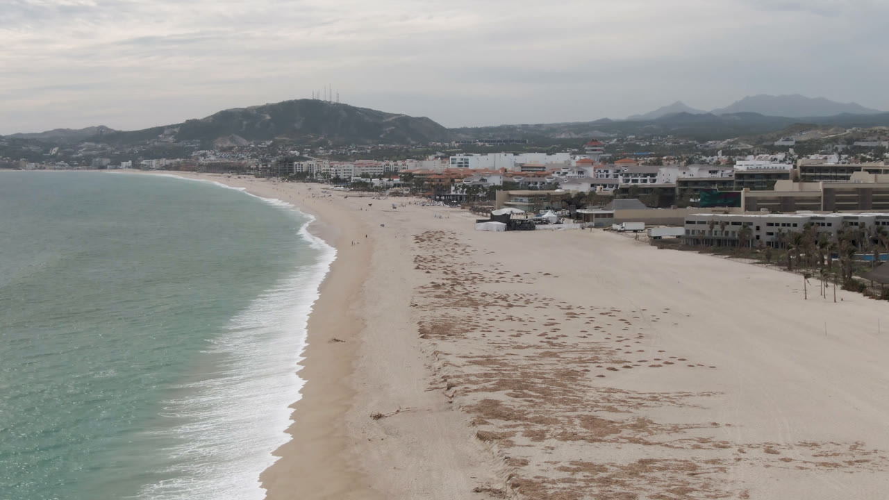 Aerial beach coastline with ocean to the left and town buildings to the right