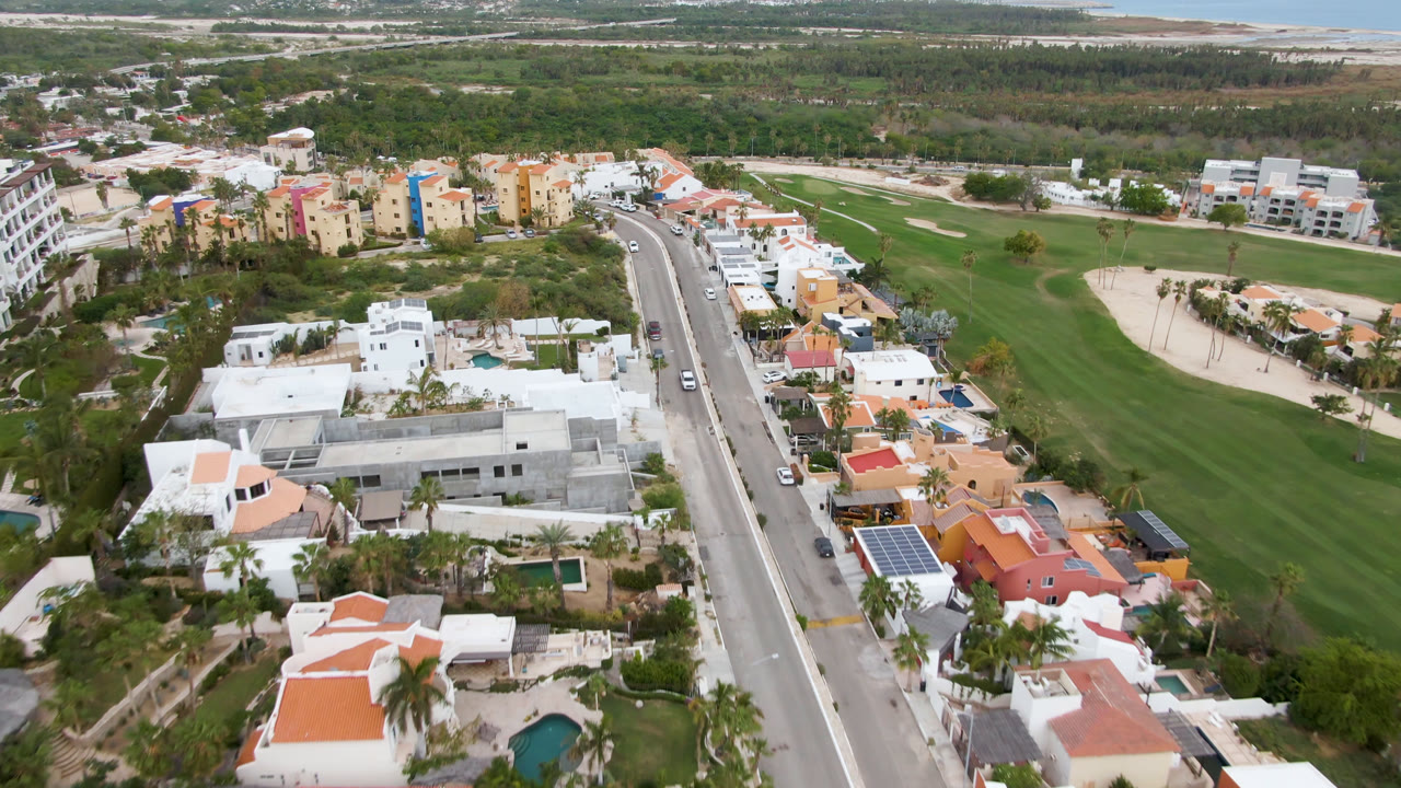 Aerial view of a road beside homes and a golf course fairway.