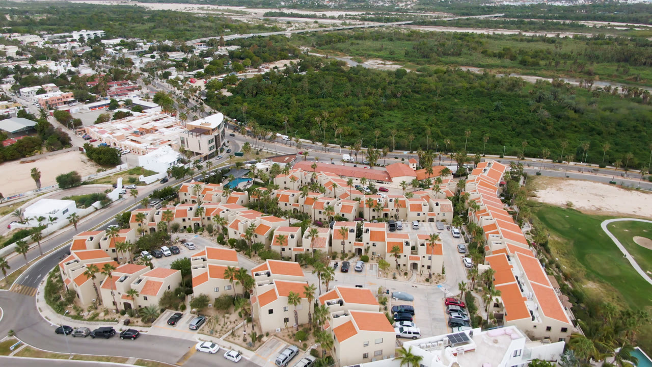 Aerial neighborhood view with rows of orange-roofed homes and a curved green lawn area.