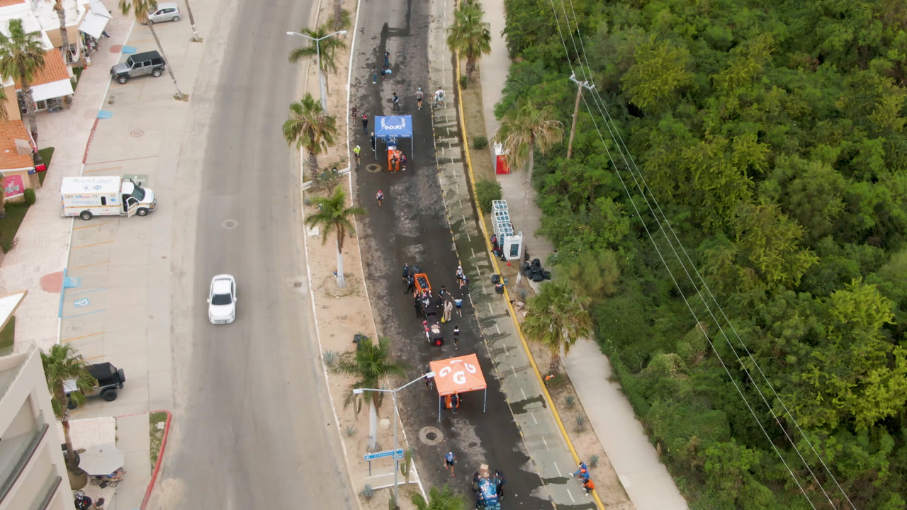Drone-like overhead view of race lane between road and green vegetation.