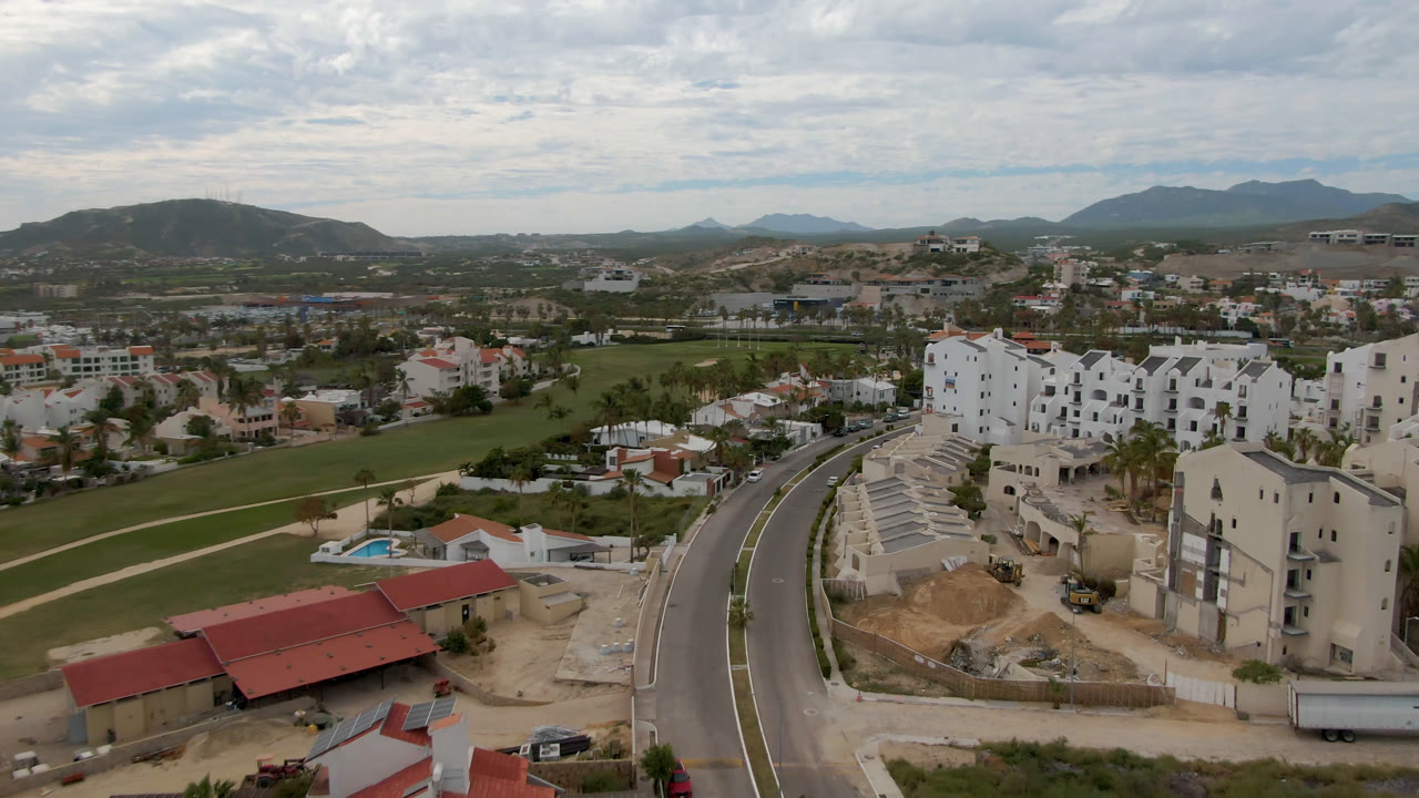 Elevated view of road, apartment buildings, golf course, and mountains.