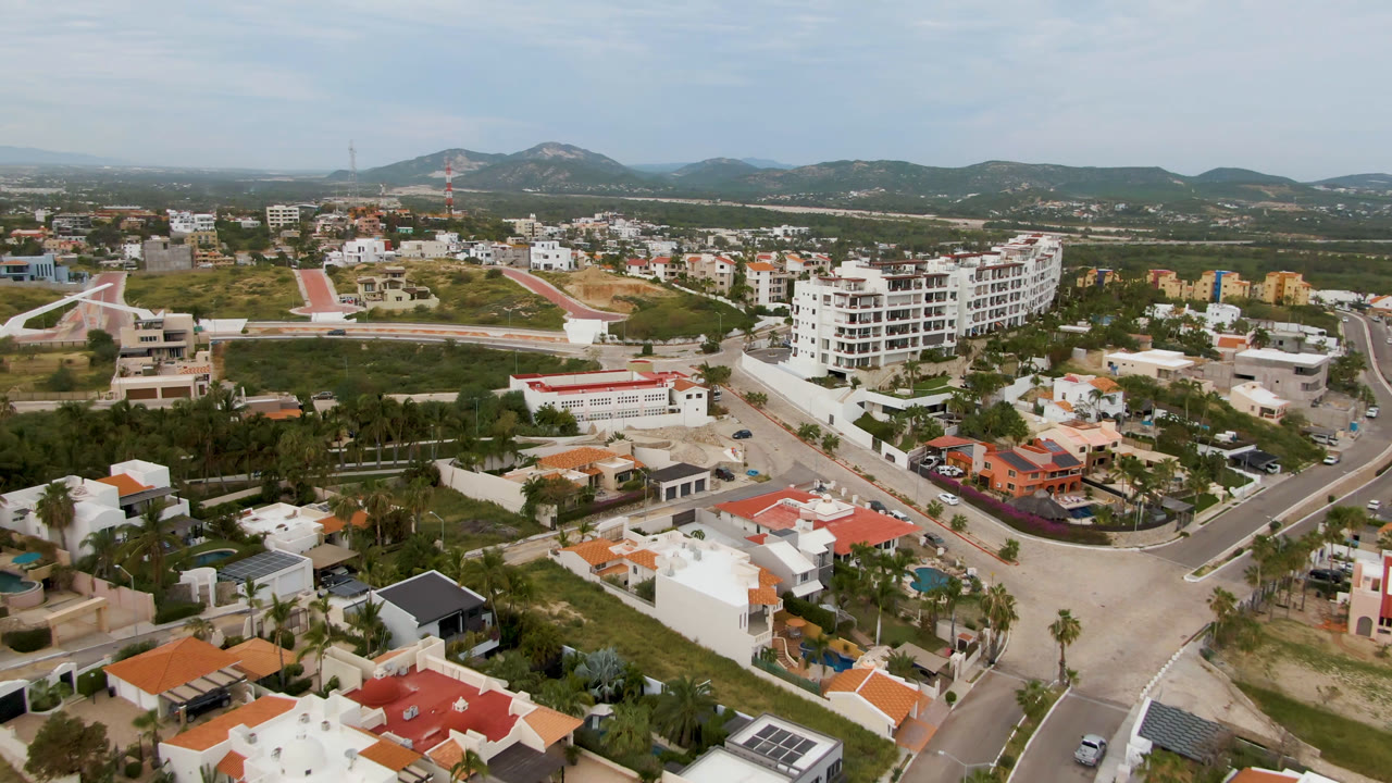 Aerial view of houses, roads, trees, and hills beyond a residential district.