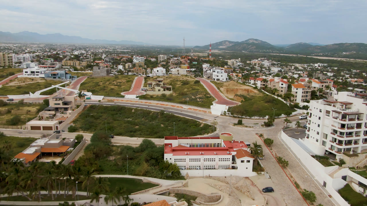 Aerial cityscape with hillside road, apartment building, and houses.