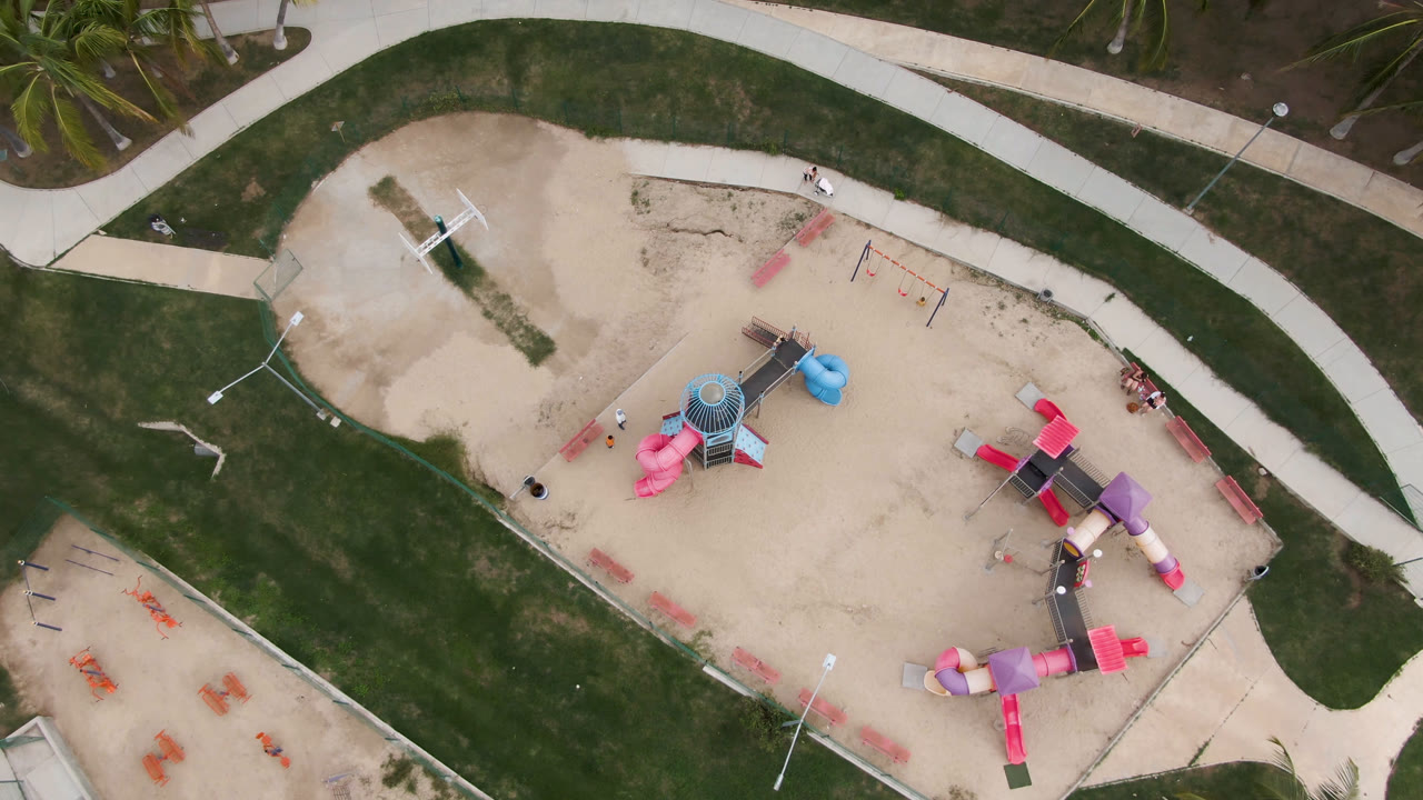 Overhead view of a sand playground with colorful slides and curved paths.