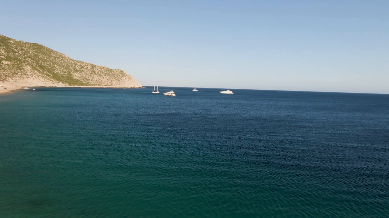 Boats sit on calm blue water near a coastal headland