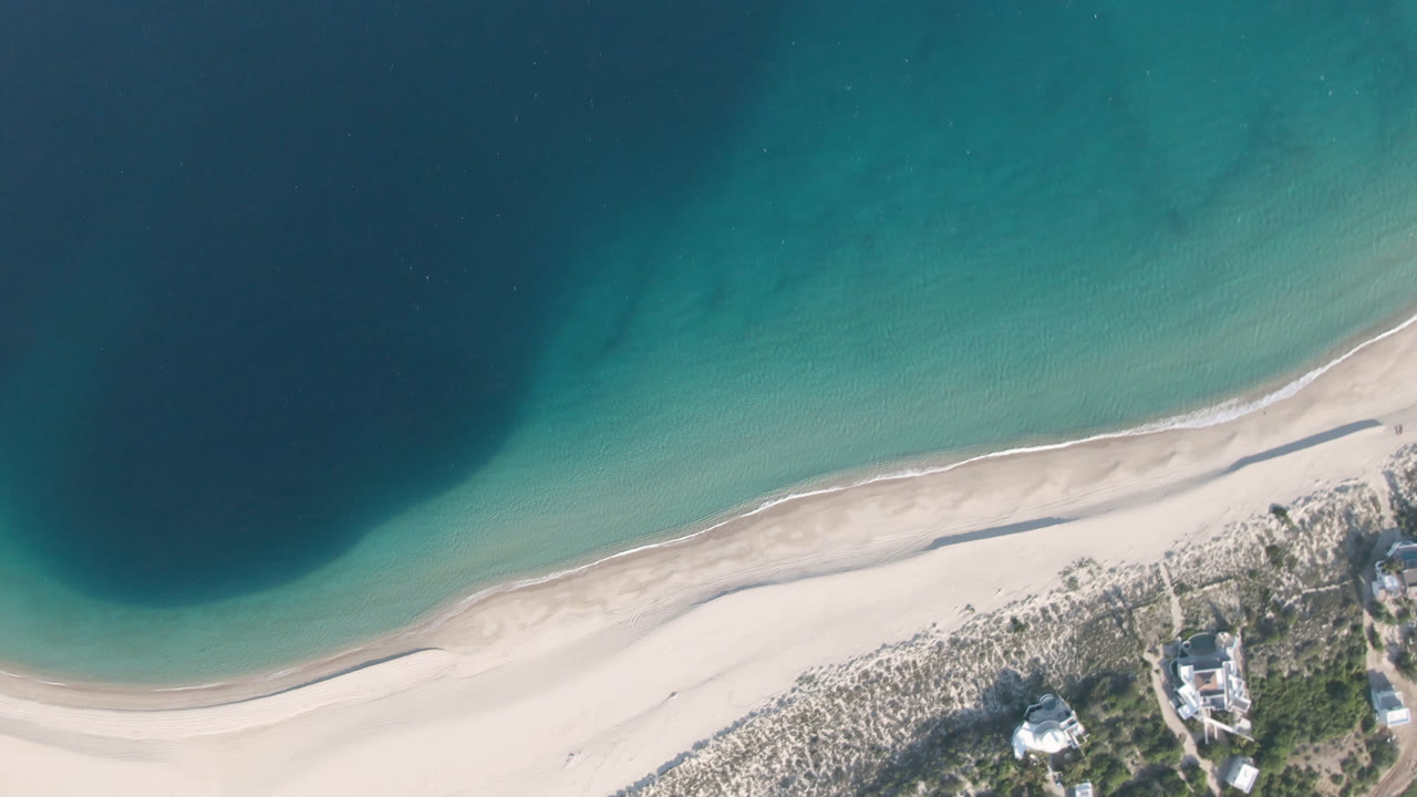 Overhead view of turquoise water and pale sand beach