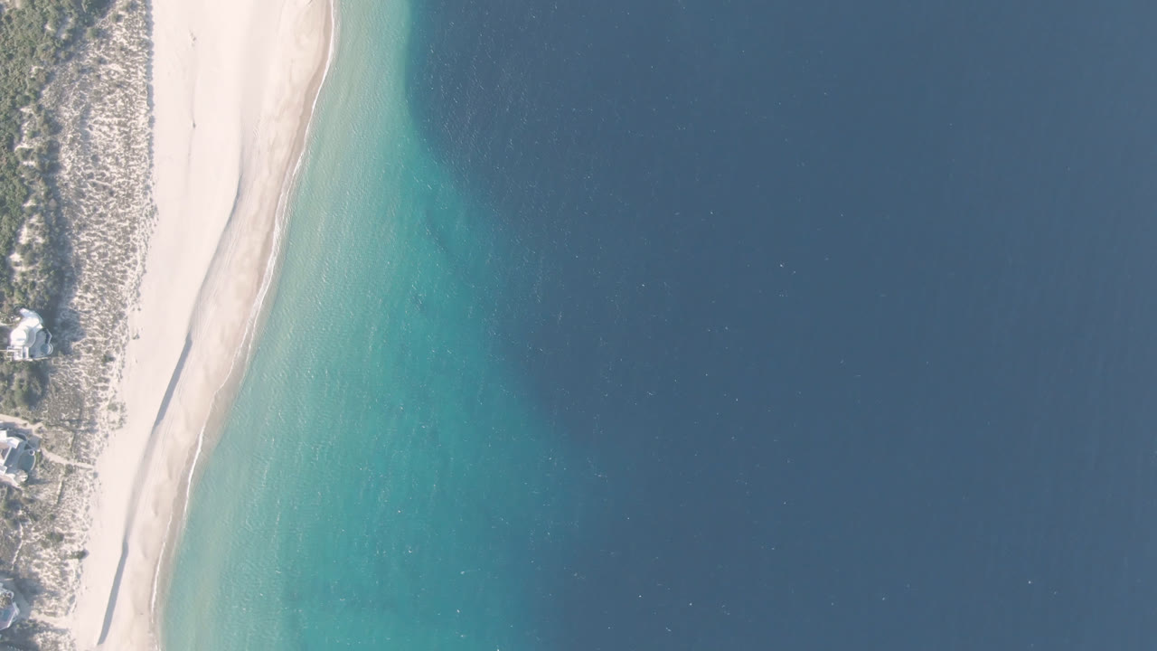 Aerial frame over Los Frailes, Baja California Sur, Mexico, showing the sandy shoreline slightly farther along the coast with no visible people.