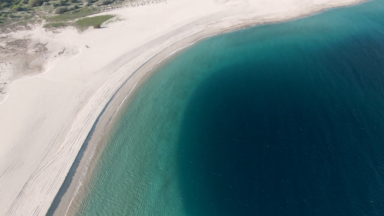 Aerial coastline with bright sand and rounded blue bay