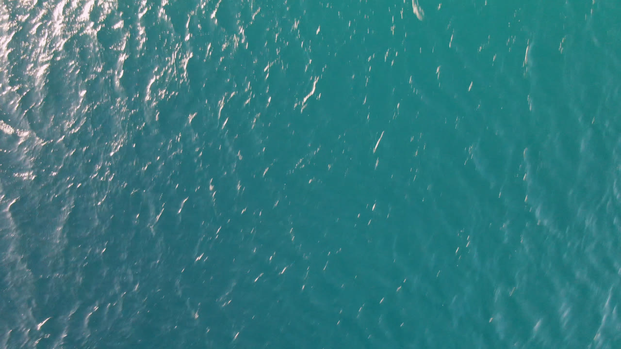 Aerial frame over Los Frailes ocean water with a denser patch of reflected sunlight near the upper left and no visible people.