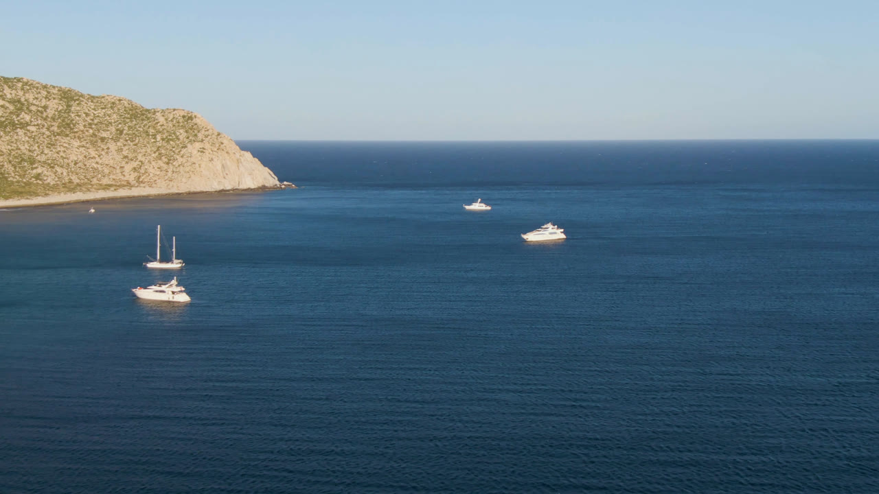 Second frame shows the same Los Frailes anchorage with sailboat masts lower in frame, two small white boats farther offshore, and no visible people.