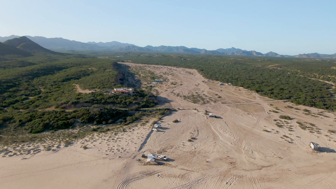 Aerial view of sandy dirt tracks crossing desert scrub toward distant mountains.