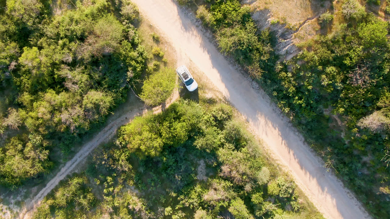 Overhead view in Los Frailes, Baja California Sur, Mexico, with a white vehicle near the upper left side of a pale dirt road and no visible people.