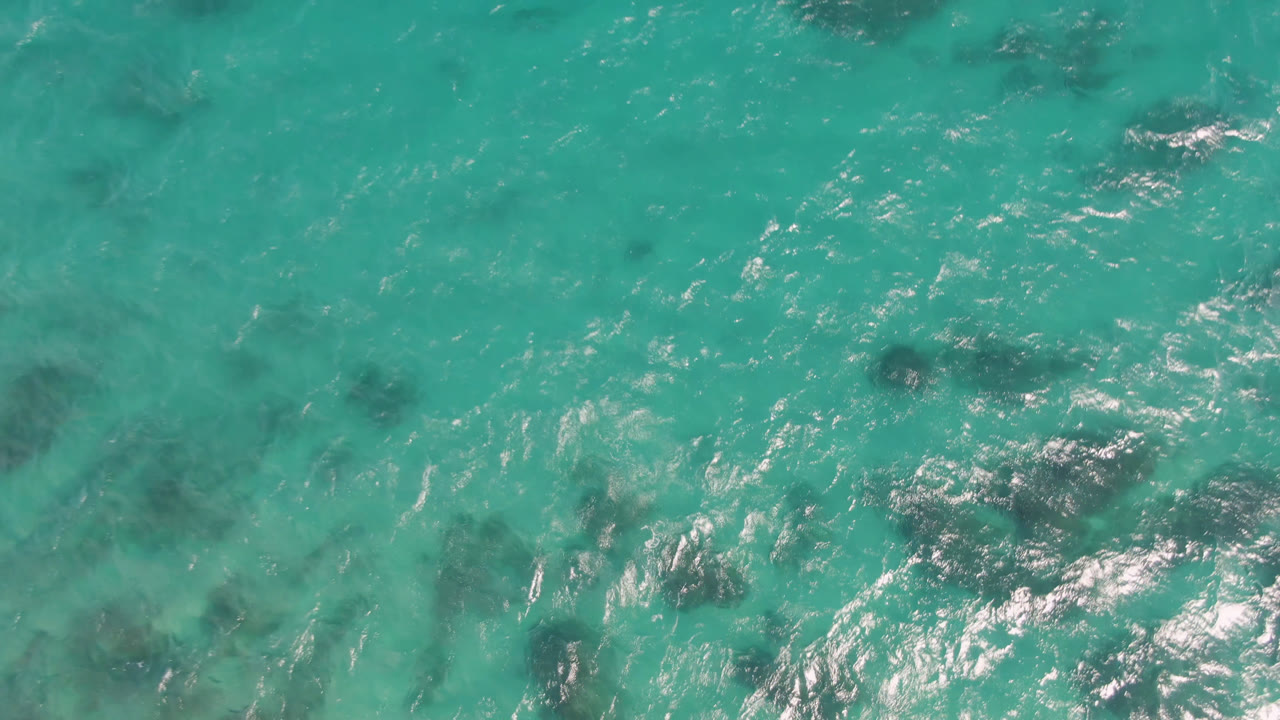 Bright turquoise ocean with darker reef-like patches and ripples