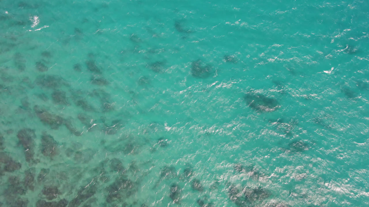 Turquoise ocean surface with dark underwater patches