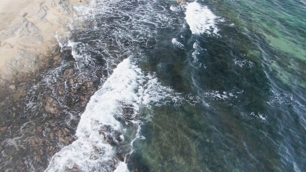 Large white breaker crossing rocks near clear green water