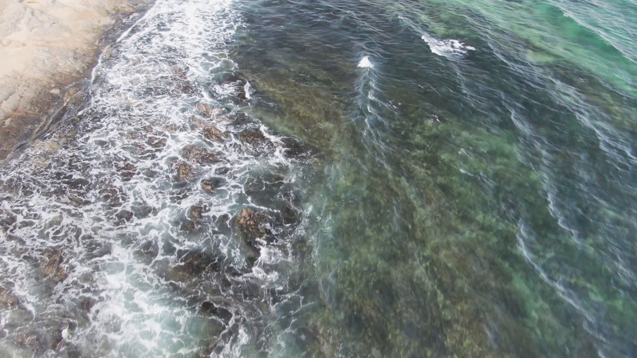 White waves curling over reef with open green water to the right