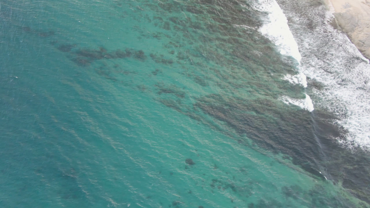 Turquoise water with darker reef patches near breaking waves