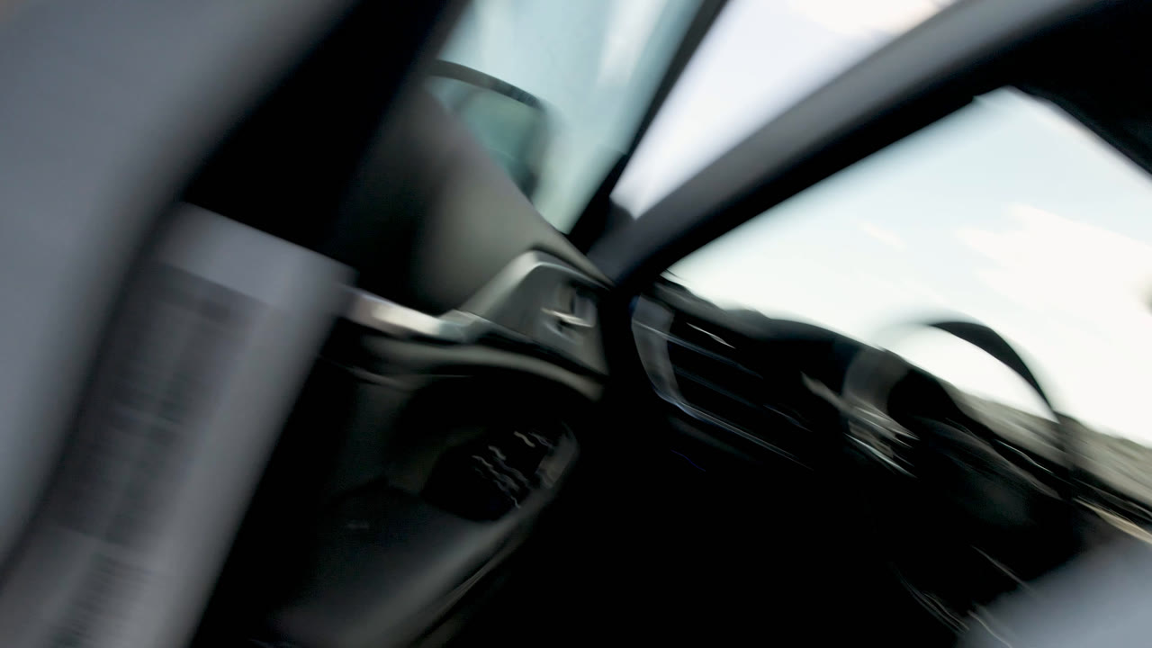 Open vehicle door with dark interior and bright sand-colored ground outside.