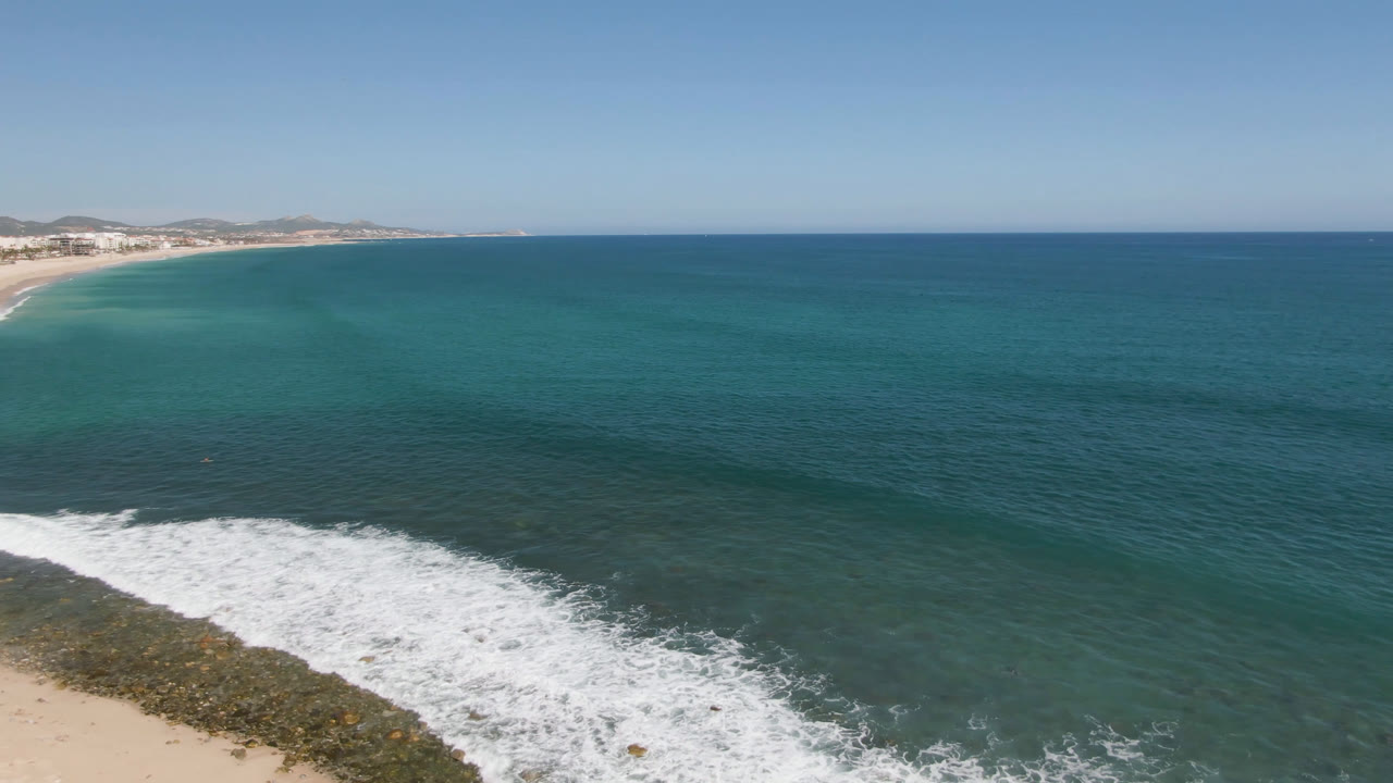 High coastal aerial with open ocean and breaking surf