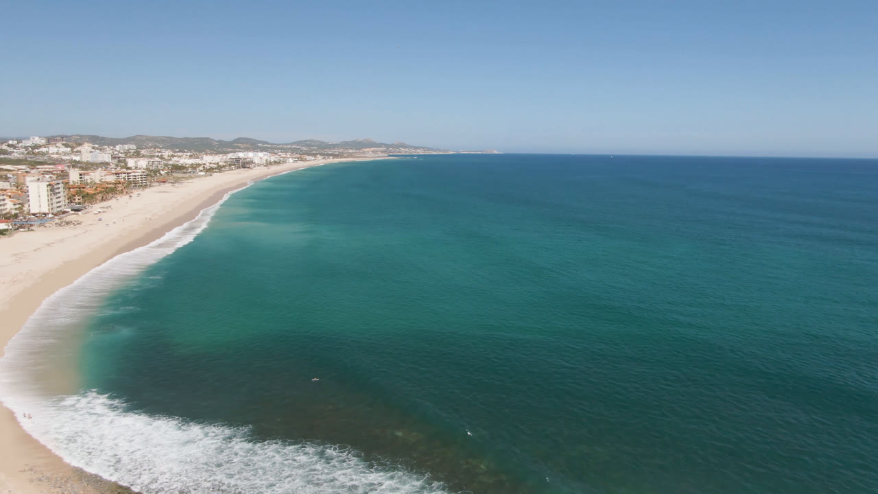 Coastal aerial with beach at left and open ocean at right.