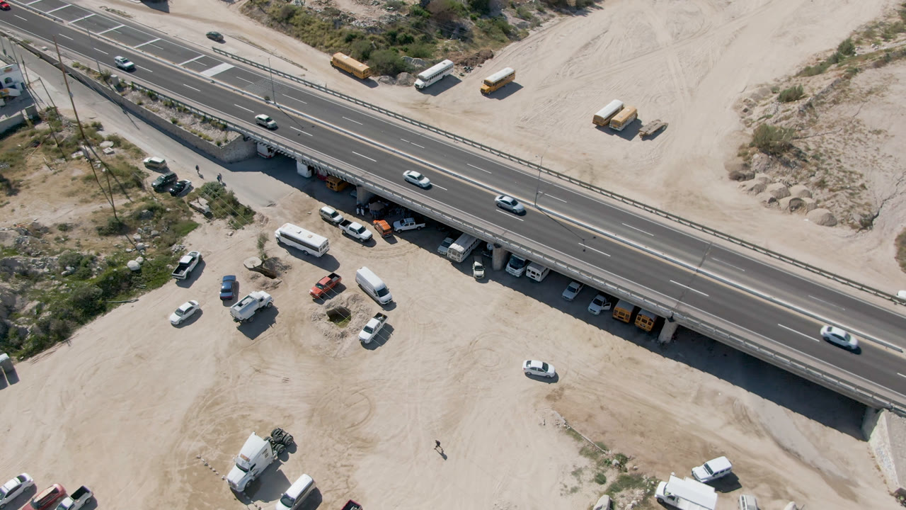 High overhead view of a road bridge with light traffic and desert lots around it.