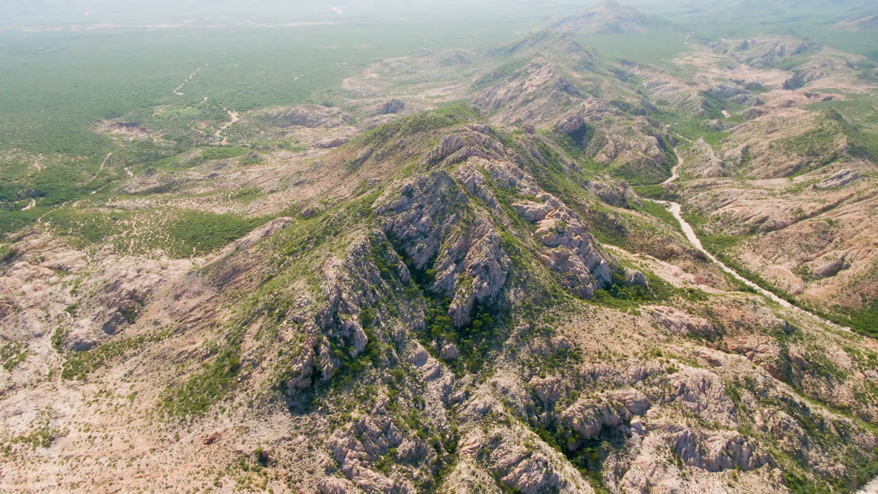 Aerial landscape of rugged desert hills with green washes and distant haze