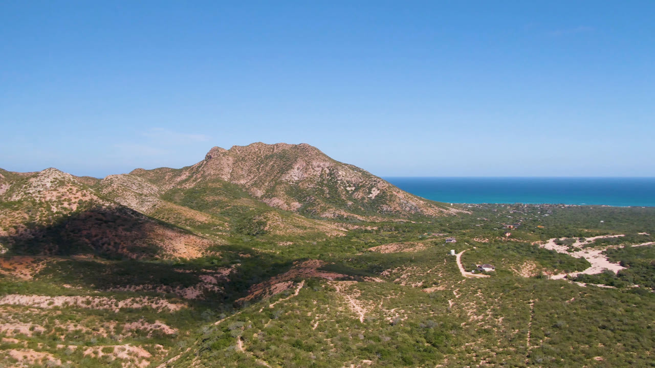 Aerial view of rocky mountains with blue ocean behind them