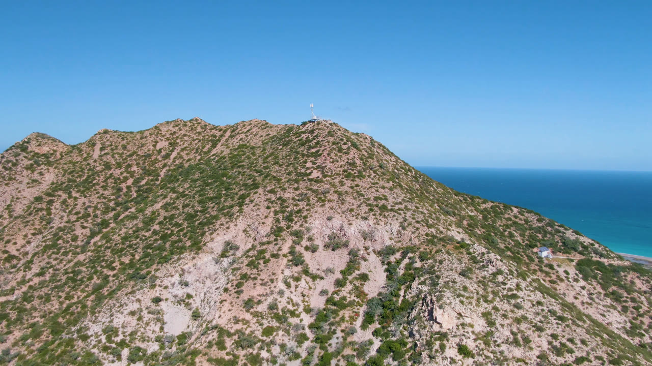 Rocky scrub mountain ridge with blue ocean behind it