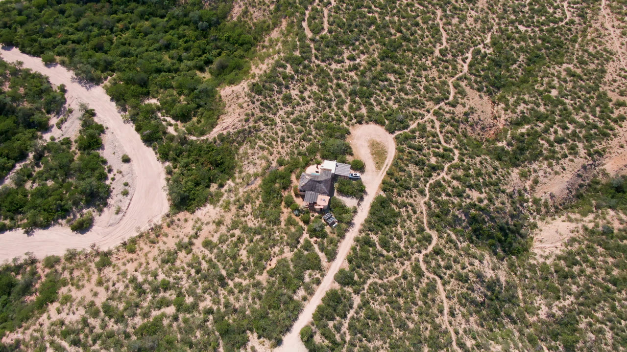 Overhead view of a small house beside dirt roads and scrubland