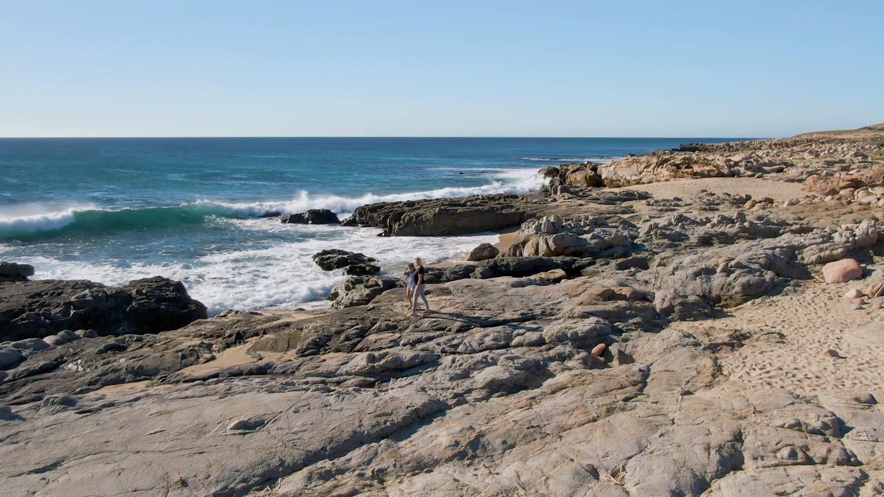 Wide rocky shoreline with two people near the surf.