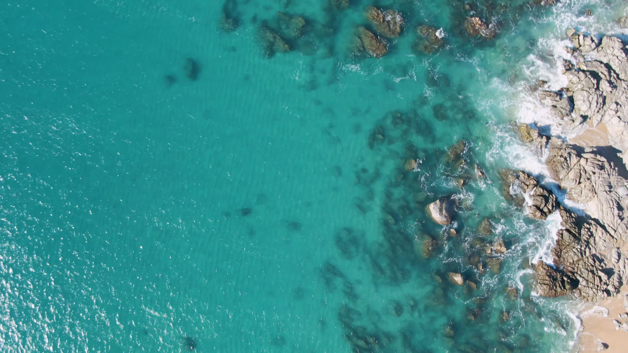 Overhead ocean water and rocky coast with surf foam