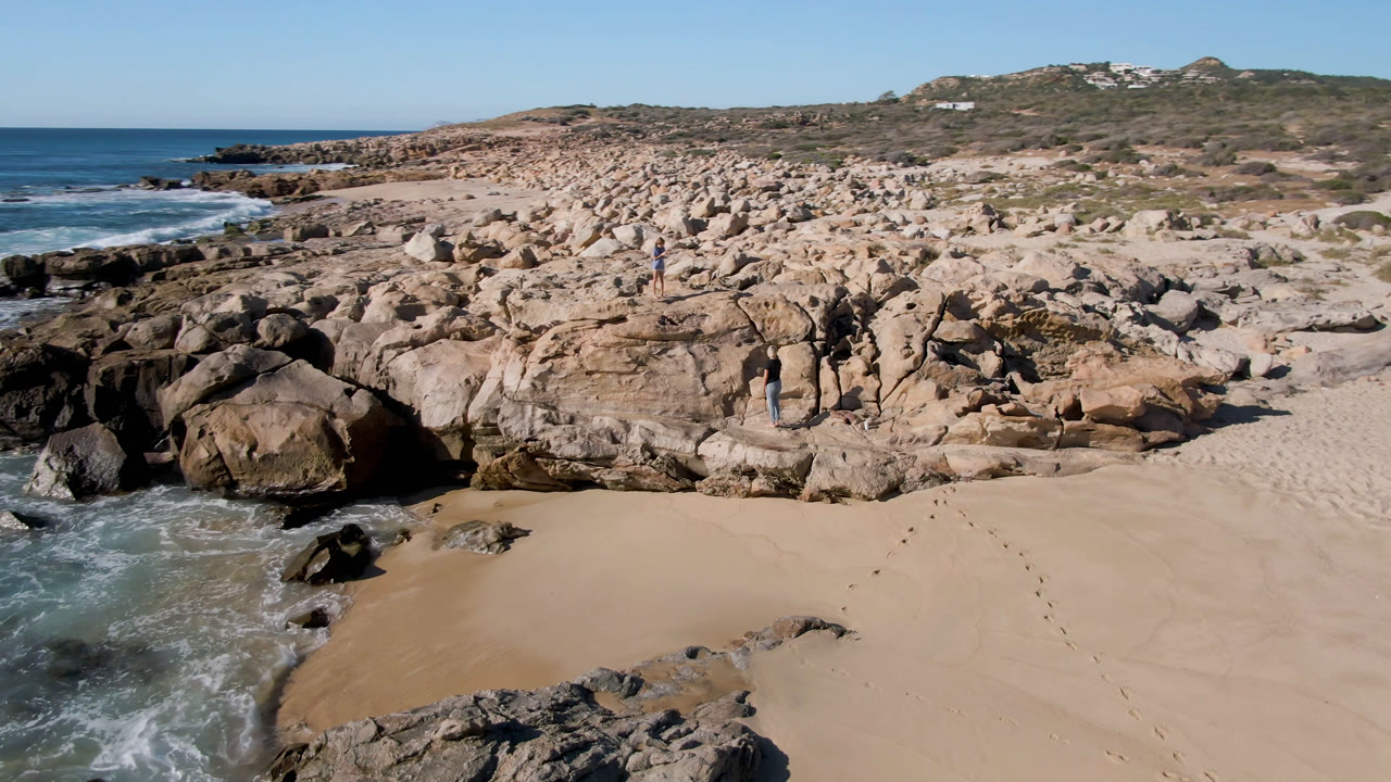 Aerial view of sandy beach, surf, and rocky shoreline